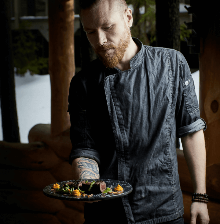 A chef presenting a plate of prepared food.